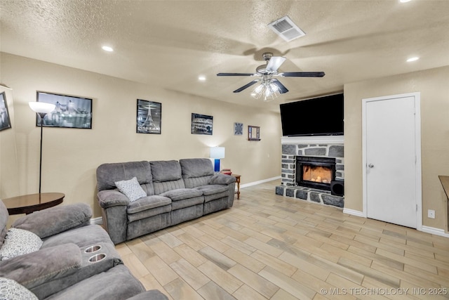 6356 S 80th E Ave Unit 25C, Tulsa, OK 74133 - living area featuring a textured ceiling, a ceiling fan, a stone fireplace, recessed lighting, and light wood finished floors