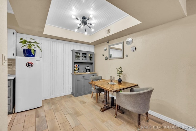 6356 S 80th E Ave Unit 25C, Tulsa, OK 74133 - dining area featuring a raised ceiling, light wood-style flooring, a chandelier, and baseboards