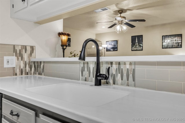 6356 S 80th E Ave Unit 25C, Tulsa, OK 74133 - detailed view of a sink, ceiling fan, light countertops, tasteful backsplash, and white cabinets