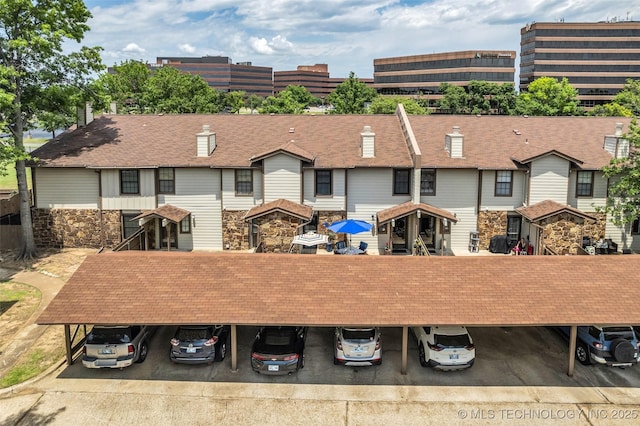 6356 S 80th E Ave Unit 25C, Tulsa, OK 74133 - rear view of house featuring covered parking, stone siding, and roof with shingles