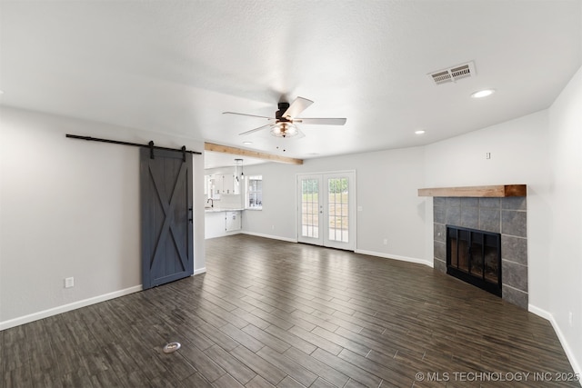 3160 E 406th Rd, Oologah, OK 74053 - unfurnished living room featuring ceiling fan, a barn door, a tile fireplace, dark wood-style flooring, and baseboards