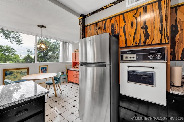 611 W 15th St Unit F1, Tulsa, OK 74127 - kitchen featuring freestanding refrigerator, white oven, light flooring, hanging light fixtures, and light stone counters