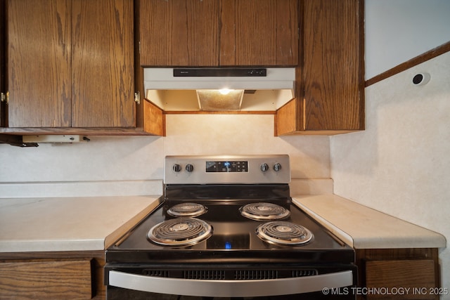 5856 E 22nd St, Tulsa, OK 74114 - kitchen with range with electric cooktop, under cabinet range hood, light countertops, and brown cabinets