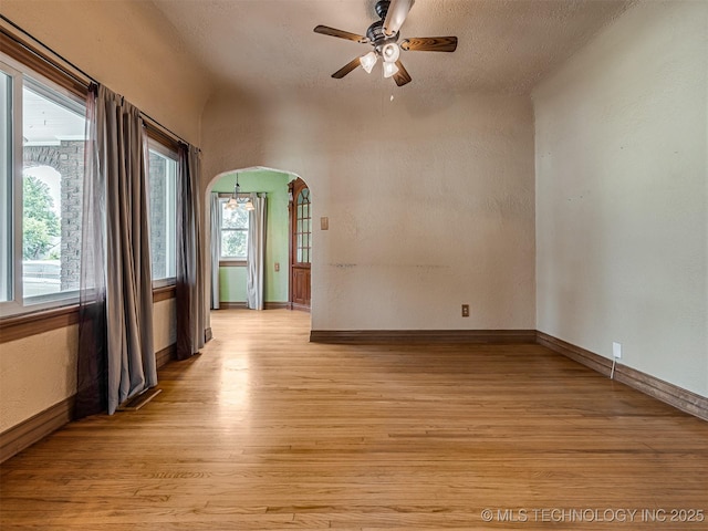 3504 E Haskell St, Tulsa, OK 74115 - unfurnished room with light wood-style floors, a ceiling fan, arched walkways, baseboards, and a textured wall
