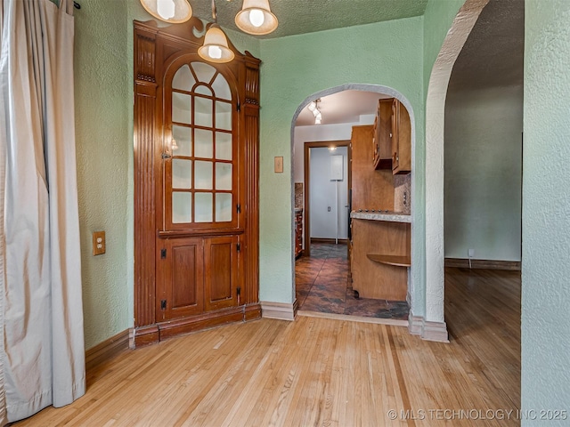 3504 E Haskell St, Tulsa, OK 74115 - foyer featuring a textured wall, arched walkways, light wood-style floors, and baseboards