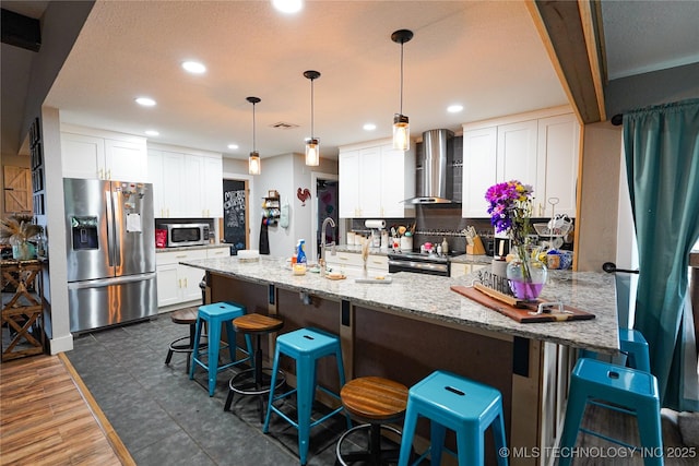 9406 S 161st Ave W, Sapulpa, OK 74066 - kitchen with wall chimney range hood, stainless steel appliances, a peninsula, light stone countertops, and recessed lighting