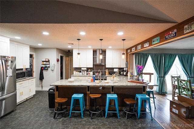 9406 S 161st Ave W, Sapulpa, OK 74066 - kitchen featuring stainless steel appliances, wall chimney exhaust hood, recessed lighting, white cabinetry, and a breakfast bar
