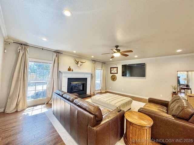 103 S Harrison Ave, Tahlequah, OK 74464 - living room featuring baseboards, ornamental molding, a glass covered fireplace, ceiling fan, and light wood-type flooring