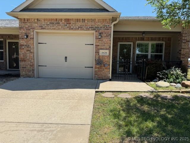 1620 Shenandoah Dr, Ardmore, OK 73401 - doorway to property featuring brick siding, an attached garage, driveway, and covered porch