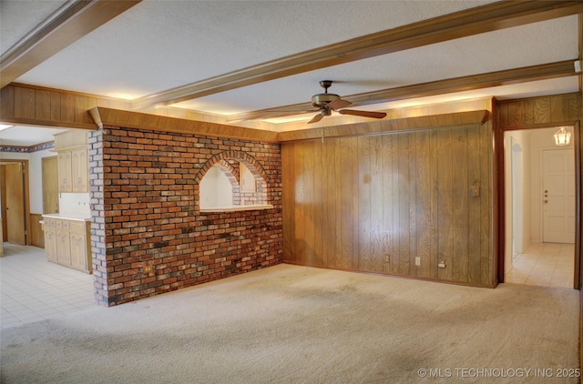 6788 E 66th Pl, Tulsa, OK 74133 - unfurnished living room with wood walls, light colored carpet, a ceiling fan, beam ceiling, and brick wall