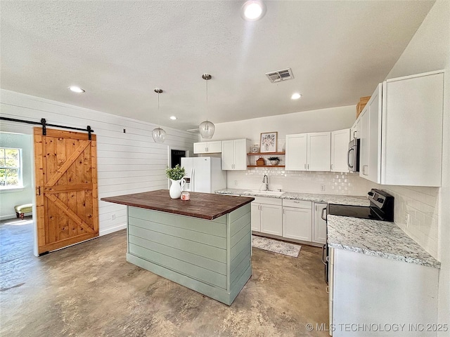 157 Canna Ln, Mcalester, OK 74501 - kitchen with white refrigerator with ice dispenser, butcher block countertops, open shelves, stainless steel microwave, and concrete flooring