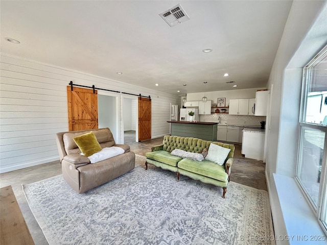 157 Canna Ln, Mcalester, OK 74501 - living room with a barn door, wooden walls, recessed lighting, and concrete floors