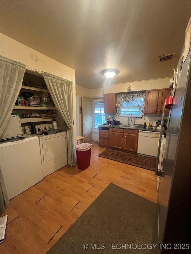 1003 E 4th St, Cushing, OK 74023 - kitchen with dishwasher, washer and clothes dryer, dark countertops, light wood-style floors, and brown cabinetry