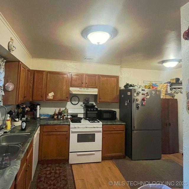 1003 E 4th St, Cushing, OK 74023 - kitchen featuring white appliances, under cabinet range hood, light wood-type flooring, and brown cabinets