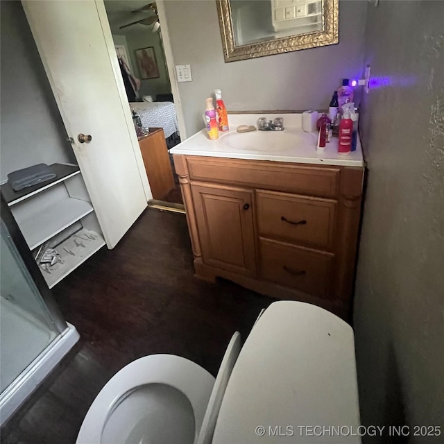 1003 E 4th St, Cushing, OK 74023 - bathroom with toilet, vanity, a stall shower, ensuite bath, and wood finished floors