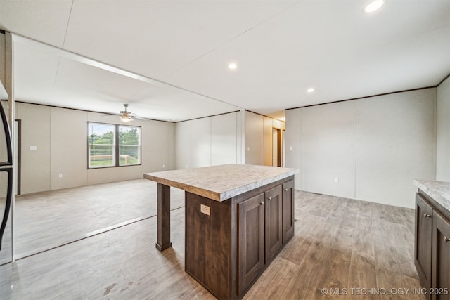 348939 E 750th Rd, Cushing, OK 74023 - kitchen featuring light countertops, dark brown cabinets, light wood finished floors, a ceiling fan, and a kitchen island