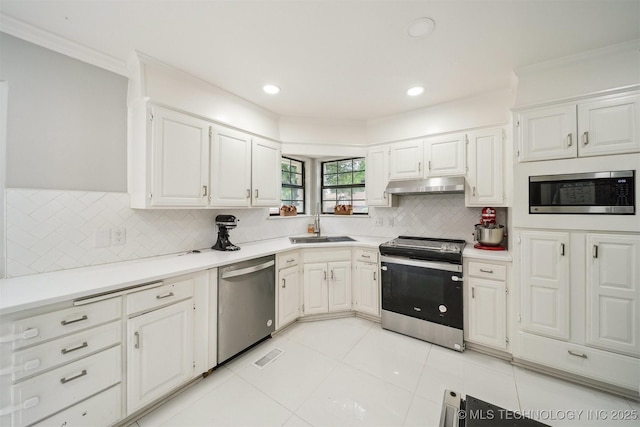 11033 E 66th St, Tulsa, OK 74133 - kitchen featuring appliances with stainless steel finishes, under cabinet range hood, crown molding, light tile patterned floors, and tasteful backsplash