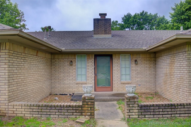 4004 S Hickory Ave, Broken Arrow, OK 74011 - view of exterior entry featuring a shingled roof, brick siding, and a chimney