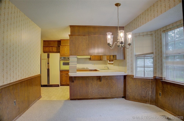 4004 S Hickory Ave, Broken Arrow, OK 74011 - kitchen with white appliances, wallpapered walls, brown cabinets, a wainscoted wall, and a sink
