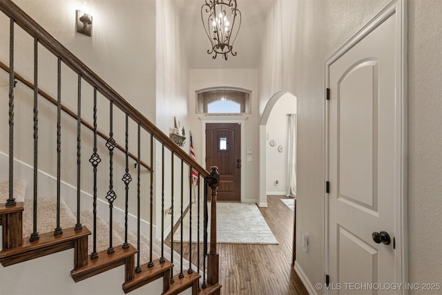 3117 S Hemlock Ct, Broken Arrow, OK 74012 - foyer entrance with arched walkways, wood finished floors, baseboards, a chandelier, and a high ceiling