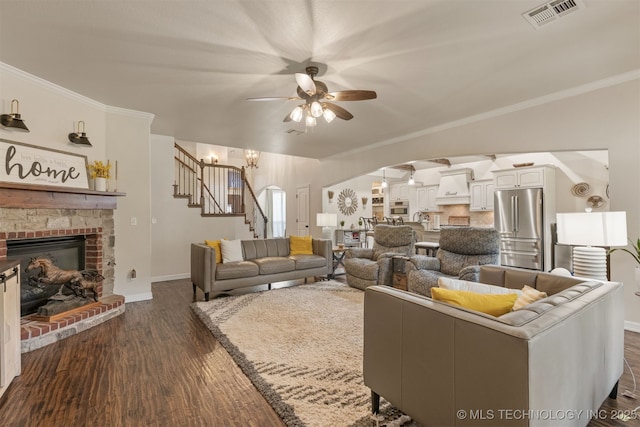 3117 S Hemlock Ct, Broken Arrow, OK 74012 - living area with arched walkways, a ceiling fan, dark wood-type flooring, stairs, and a fireplace