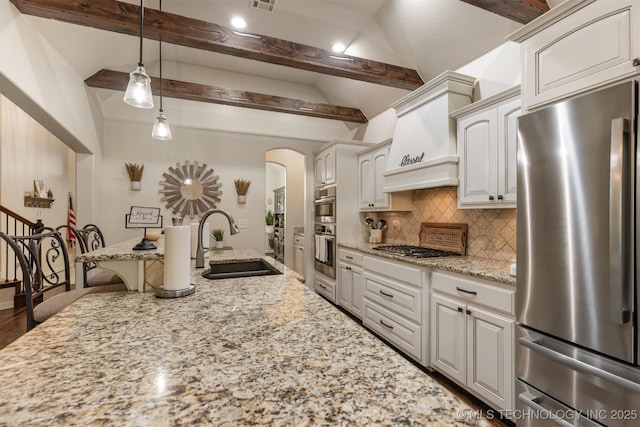 3117 S Hemlock Ct, Broken Arrow, OK 74012 - kitchen featuring appliances with stainless steel finishes, a sink, arched walkways, backsplash, and light stone countertops