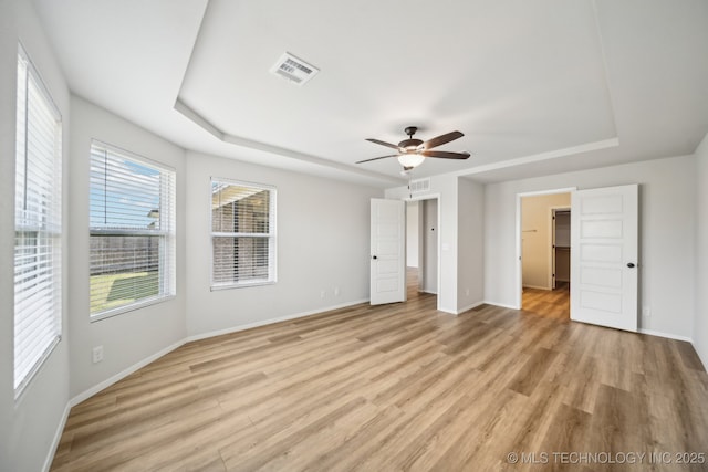 12503 N 130th Ave E, Collinsville, OK 74021 - unfurnished bedroom featuring a tray ceiling, light wood finished floors, and baseboards