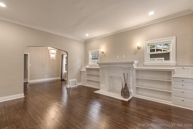 2305 E 13th St, Tulsa, OK 74104 - unfurnished living room with arched walkways, crown molding, plenty of natural light, baseboards, and wood finished floors