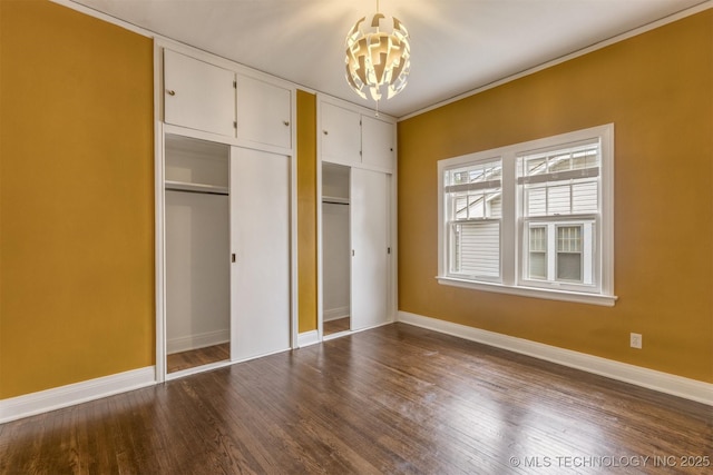 2305 E 13th St, Tulsa, OK 74104 - unfurnished bedroom with a chandelier, baseboards, dark wood finished floors, two closets, and ornamental molding