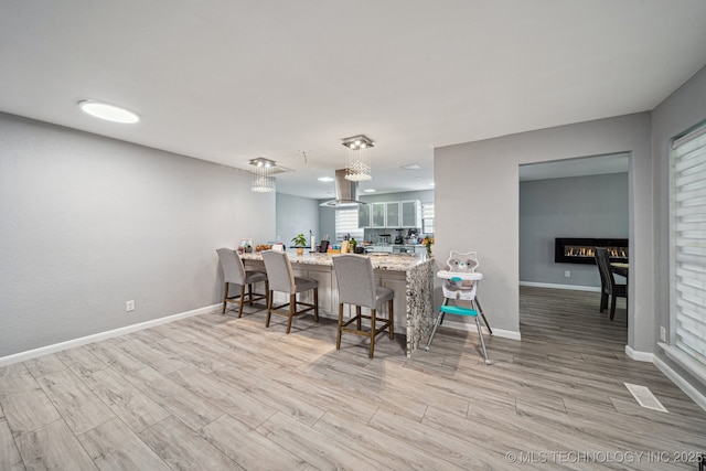 6407 S 110th E Ave, Tulsa, OK 74133 - kitchen featuring wood finished floors, a peninsula, baseboards, a breakfast bar, and island exhaust hood