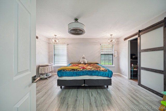 6407 S 110th E Ave, Tulsa, OK 74133 - bedroom with a chandelier, a barn door, wood finished floors, and baseboards