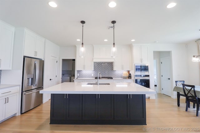 13657 S 21st Ct E, Bixby, OK 74008 - kitchen featuring appliances with stainless steel finishes, washer and dryer, a sink, tasteful backsplash, and light wood-style floors
