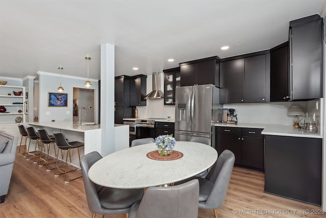 5206 S Harvard Ave Unit 308, Tulsa, OK 74135 - kitchen featuring appliances with stainless steel finishes, dark cabinets, wall chimney range hood, light wood-type flooring, and crown molding