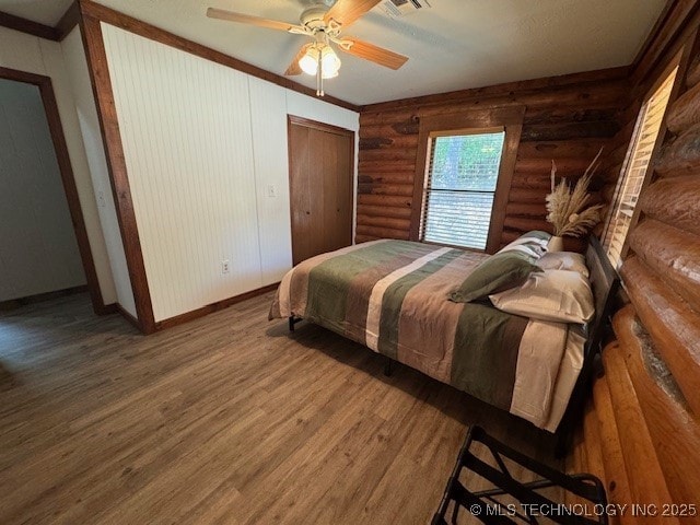 13248 Spelling Rd, Davis, OK 73030 - bedroom with log walls, baseboards, wood finished floors, a ceiling fan, and ornamental molding