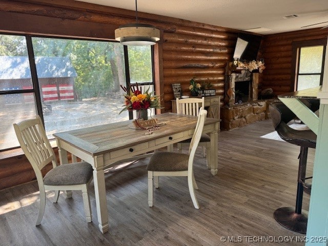 13248 Spelling Rd, Davis, OK 73030 - dining space with wood finished floors, rustic walls, plenty of natural light, and a stone fireplace