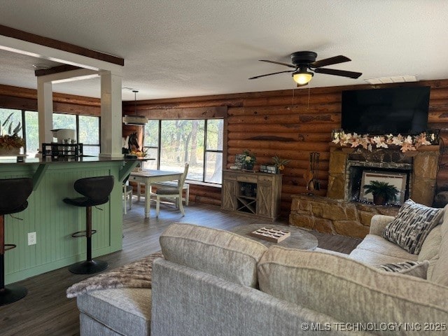 13248 Spelling Rd, Davis, OK 73030 - living area with rustic walls, a fireplace, wood finished floors, ceiling fan, and a textured ceiling