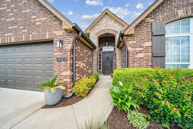 9508 N 96th E Pl, Owasso, OK 74055 - doorway to property featuring brick siding, a garage, and driveway