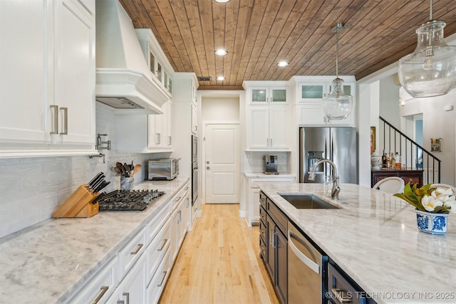 5918 E 127th Pl S, Tulsa, OK 74008 - kitchen featuring custom range hood, appliances with stainless steel finishes, white cabinets, light wood-style flooring, and a sink