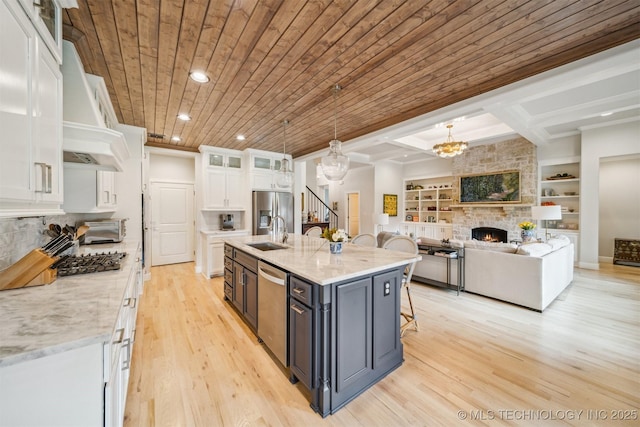 5918 E 127th Pl S, Tulsa, OK 74008 - kitchen featuring white cabinets, appliances with stainless steel finishes, light wood-style floors, a chandelier, and a large fireplace