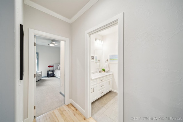 5918 E 127th Pl S, Tulsa, OK 74008 - hallway with crown molding, a sink, light wood-style flooring, and baseboards