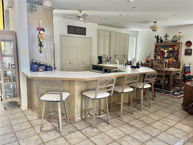 5168 Tower Dr, Kingston, OK 73439 - kitchen with cream cabinetry, ceiling fan, a kitchen breakfast bar, and light countertops