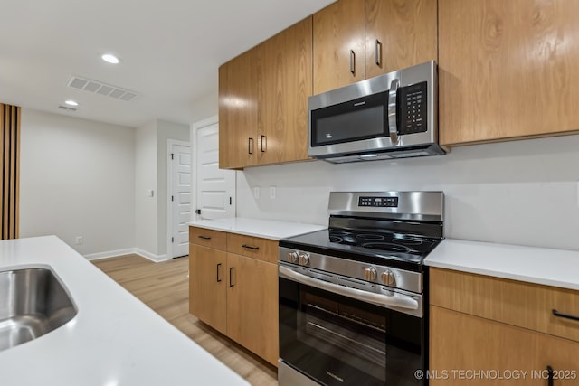 1448 N Main St Unit 2, Tulsa, OK 74106 - kitchen with stainless steel appliances, light countertops, light wood-style flooring, baseboards, and a sink