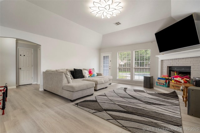 1105 N Joshua Ave, Broken Arrow, OK 74012 - living area with light wood-type flooring, vaulted ceiling, arched walkways, a brick fireplace, and baseboards