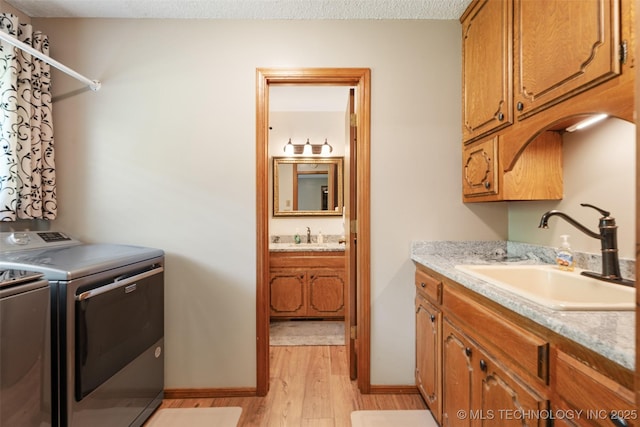 1485 Old Ketchum Rd, Langley, OK 74350 - laundry area featuring washing machine and clothes dryer, light wood-style floors, cabinet space, baseboards, and a textured ceiling