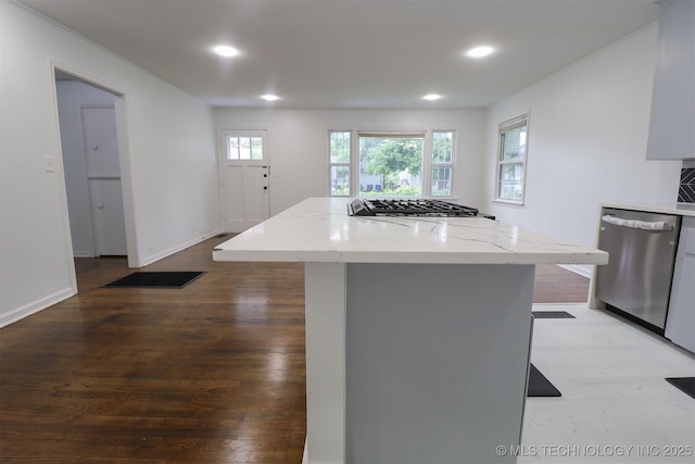4607 E 4th Pl, Tulsa, OK 74112 - kitchen featuring appliances with stainless steel finishes, recessed lighting, light wood-type flooring, a kitchen island, and light stone counters