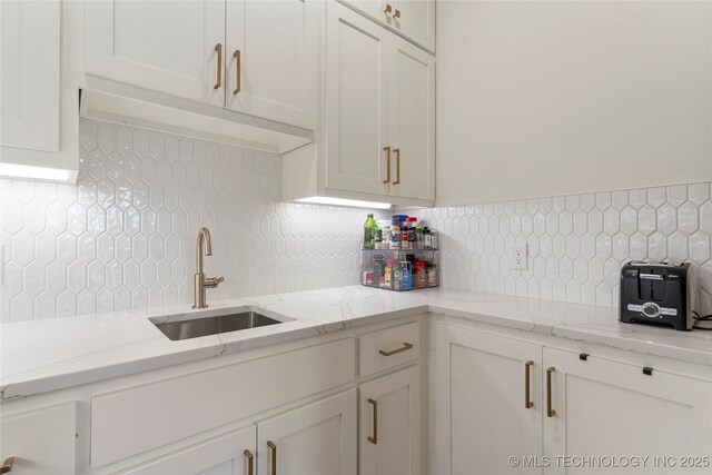 10215 E 121st Pl S, Bixby, OK 74008 - kitchen with a sink, decorative backsplash, white cabinetry, and light stone countertops