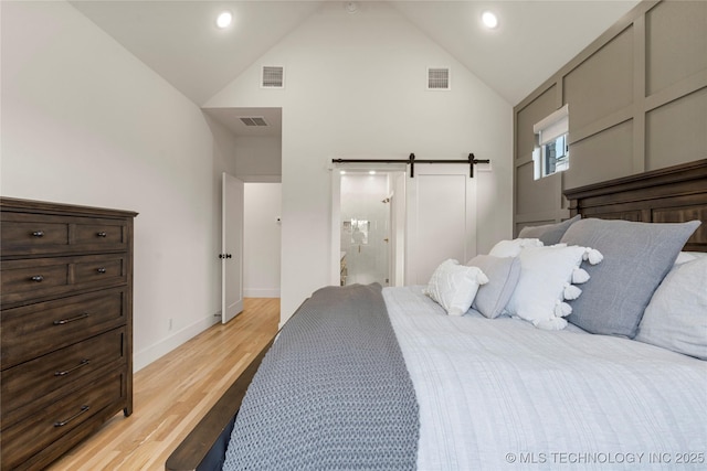 10215 E 121st Pl S, Bixby, OK 74008 - bedroom featuring high vaulted ceiling, light wood-style flooring, a barn door, baseboards, and ensuite bath