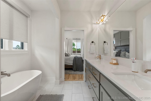 10215 E 121st Pl S, Bixby, OK 74008 - ensuite bathroom with double vanity, a freestanding bath, tile patterned flooring, and baseboards