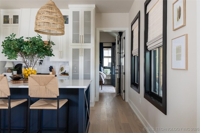 67 Lower Green Way Unit B, Carlton Landing, OK 74432 - kitchen with wood finished floors, decorative backsplash, white cabinetry, light countertops, and hanging light fixtures