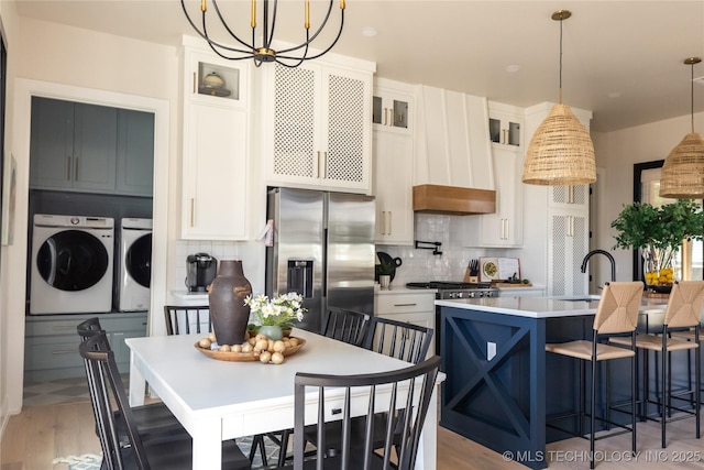 67 Lower Green Way Unit B, Carlton Landing, OK 74432 - kitchen with appliances with stainless steel finishes, separate washer and dryer, a chandelier, backsplash, and white cabinets